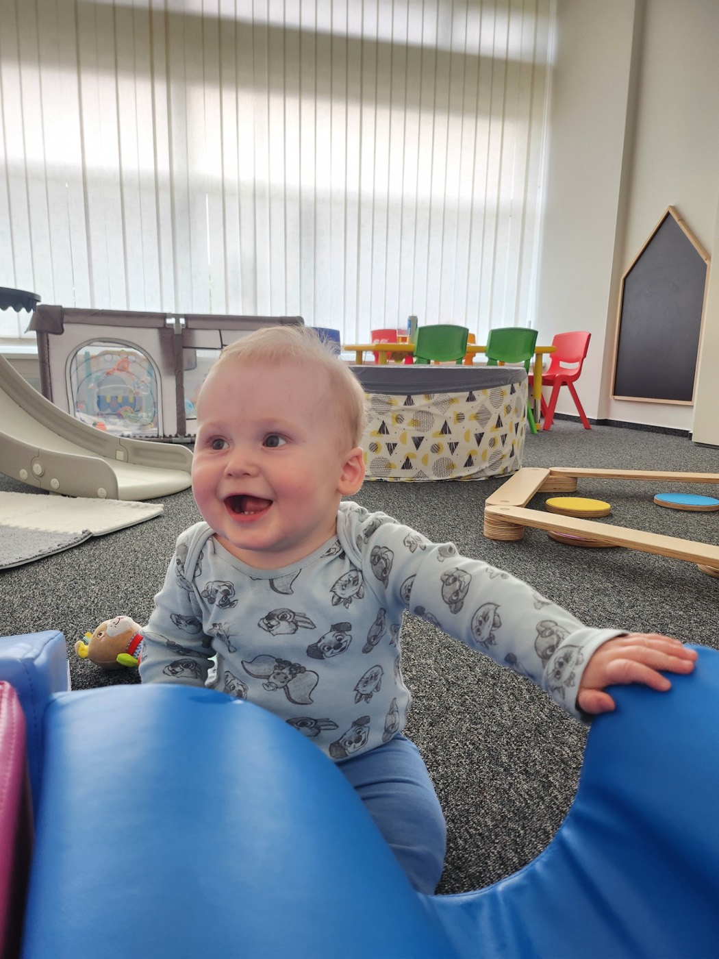 A smiling toddler among the soft obstacles in the Kentíci playroom