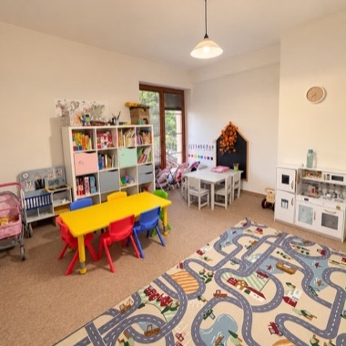 Classroom with little tables, bookshelf and a play kitchen